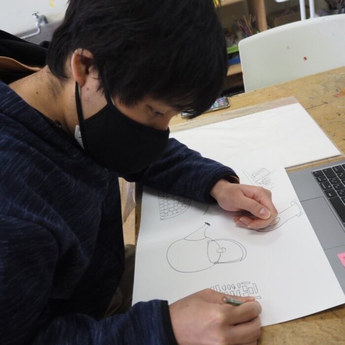 写真；内田さんが絵を描いています。