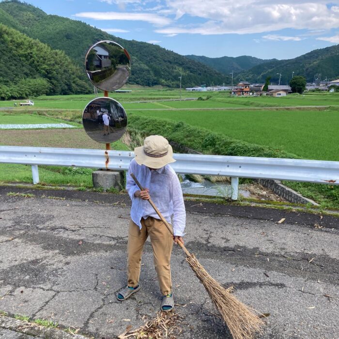 写真：小清水が店頭を竹箒で掃いています。