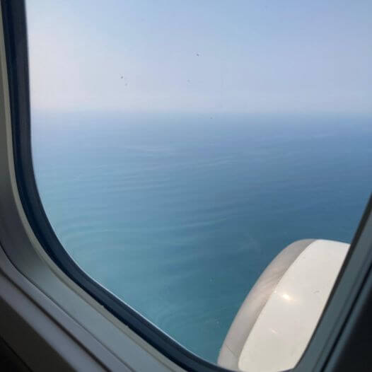 写真：飛行機の窓から海が見えています。
