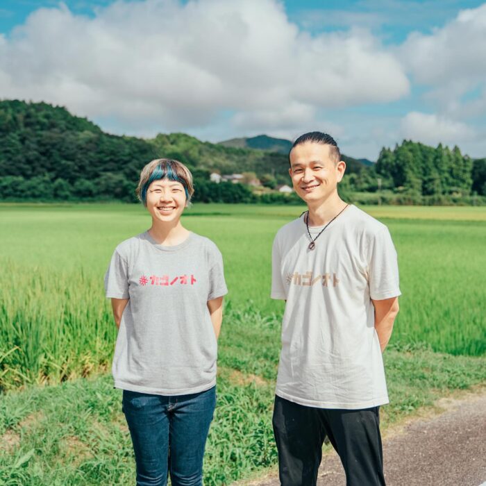 写真：カゴノオトの前の田んぼの前でカゴノオトTシャツを着ている前と小清水です